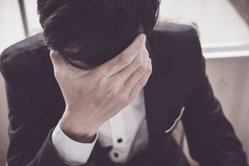A stressed out business man holds his head in despair as he fears that he will have to file for...