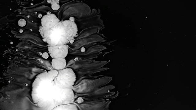 White liquid splattered over wet black screen background. Close-up shot