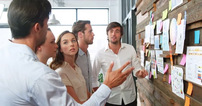 Business executives discussing over sticky notes and graph charts