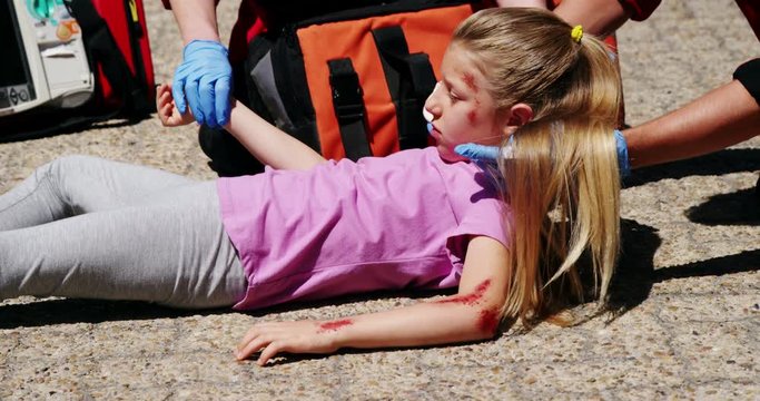 Paramedics examining injured girl