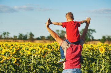 father with child in a field of blooming sunflowers , father's day