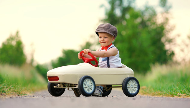 lachender kleiner Junge im Tretauto