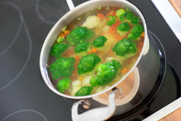 Nutritional soup with green broccoli in pan on hob