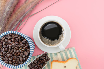 Coffee cup and coffee beans on pink background