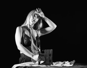 sexy blonde woman in men's pants and a bra, ironing white shirt with old iron. retro style, black and white