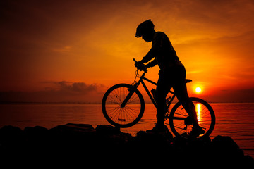 Obraz premium Silhouette of bicyclist enjoying the view at seaside. Outdoors.