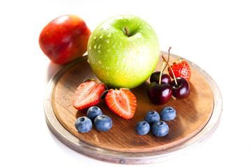 Fresh fruits on a wooden cutting board on a white background