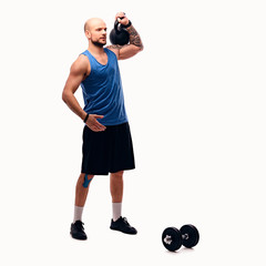 Shaved head athletic male doing workouts with kettlebell.