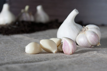 Garlic. Garlic bulbs with cloves on burlap background, concept healthy lifestyle. In the background a small patch of garlic.