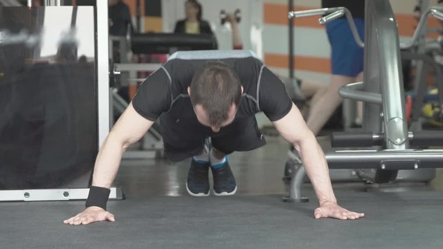 Fitness man doing push-ups exercise intense training in gym.