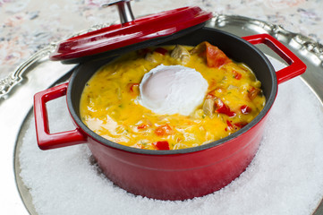 Sunny side up fried egg and mushrooms in a nested stack of old cast iron frying pans in a rustic kitchen, overhead view