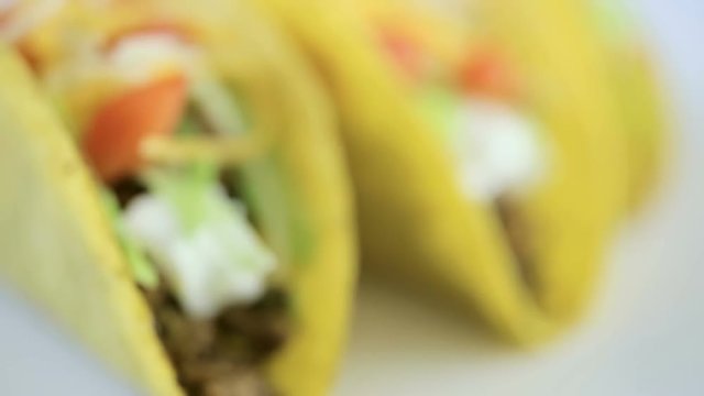 Fresh beef tacos in hard yellow corn taco shell with sour cream and shredded cheese