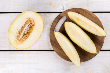 Three slices of fresh melon on the wooden kitchen board