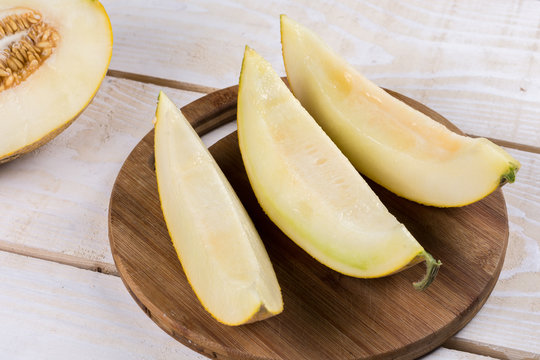 Three slices of fresh melon on the wooden kitchen board