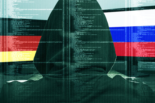 Hacker working on a cyber attack on Germany and Russia. Concept of hacking into the computer. Ger and Rus flag on the screen. German and Russian flag on the screen.