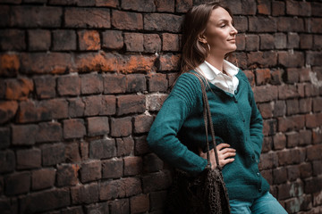 Loft style, woman standing near brick dark wall, ancient, looking away, copy space, casual