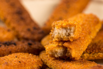 Fried fish meat sticks on the plate above wooden planks  table