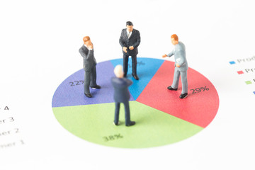 Miniature model of businessman thinking with project for presenting investment concept on graph.