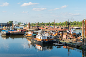 Fototapeta na wymiar The Travehafen basin in the Steinwerder district of Hamburg. The port is a harbor basin for river vessels. Plenty of barges lies at the pier. The Travehafen is a river port, inside the deep water port