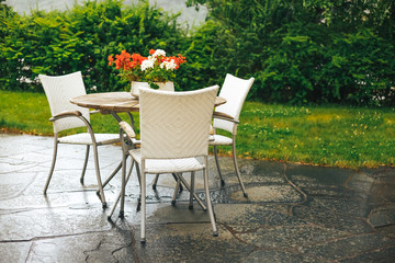 Beautiful terrace or balcony with small table, chairs and flowers after rain