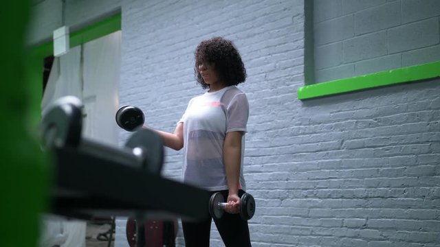 African American woman working with dumbbells in the gym