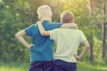 Fototapeta premium Two boys walking hugging in the park