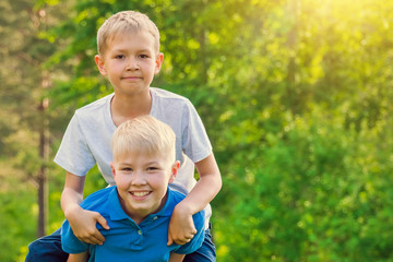 Fototapeta premium Boy sitting on the back of a friend in the sunshine