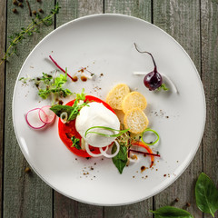 Caprese salad made of fresh mozzarella, tomato and herbs on a table. Italian healthy food on a plate. Top view.
