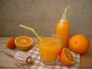 Freshly squeezed orange juice in a glass and a bottle on the rustic table.