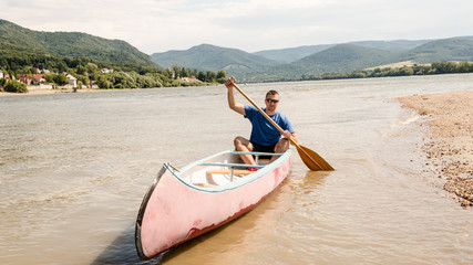 young man in sunglass canoing on Hungarian river in summer