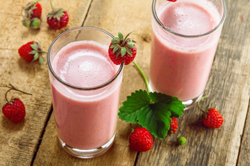 Fresh strawberry milkshake on a wooden table. Healthy fruit smoothie drink. Top view, close-up shot.