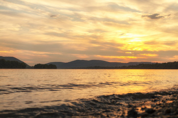 vibrant yellow summer sunset by river on beach