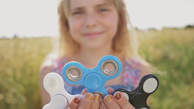 The girl is holding spinners white, blue and black colour. Stress relieving toy.