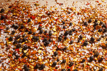 A very close view of coarsely ground red pepper, salt and whole black pepper seasoning.