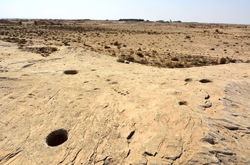 Rocky deserted landscape with ancient petroglyphs at Jebel Jassassiyeh site in Northern Qatar.