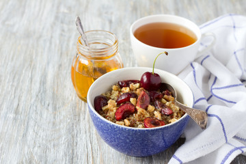Healthy delicious vegan breakfast. Quinoa with fresh cherries, walnuts and honey on the blue background