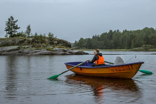A girl alone in a boat sailing with oars in Lake Ladoga, Russia