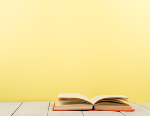 education and wisdom concept - open book on wooden table, color background