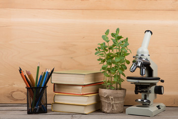 Education concept - books and microscope on the desk in the auditorium