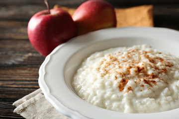 Delicious rice pudding with cinnamon on wooden background