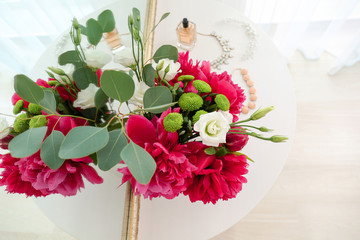 Bouquet of beautiful flowers on light table near mirror