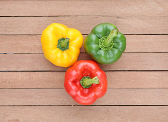 Green , red and yellow bell pepper on wood background.