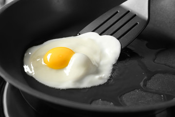 Delicious over easy egg and turner in pan, closeup