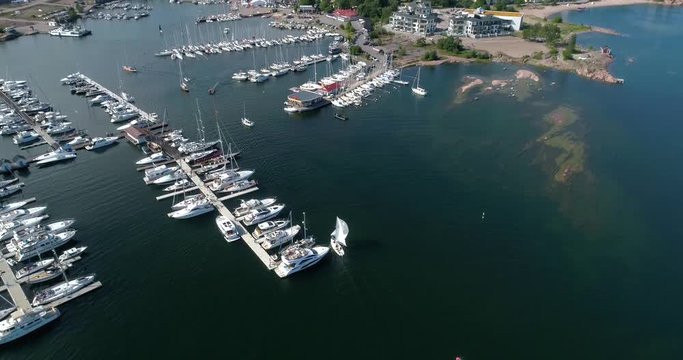 Hanko, Cinema 4k aerial tilt view of a sailboat entering ita-satama, full of boats and revealing the city, on Hango regatta day, in Uusimaa, Finland