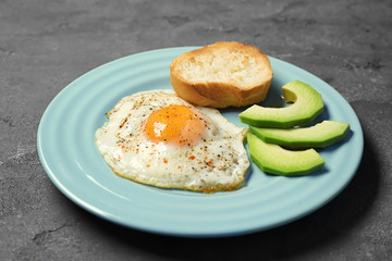 Delicious over easy egg with toast and avocado slices on kitchen table