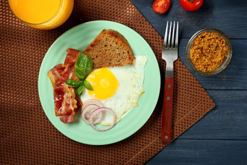 Delicious over easy egg with toast and bacon on kitchen table