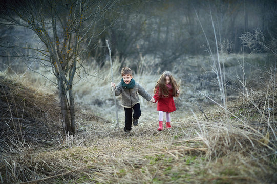 ittle boy and girl stand in a field in early spring