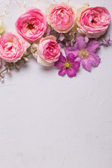Fresh pink  roses and violet summer clematis flowers on grey background.