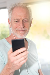 Obraz premium Portrait of mature man listening music with earphones, light effect