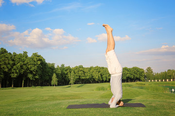 Fototapeta na wymiar Young man practicing yoga outdoors